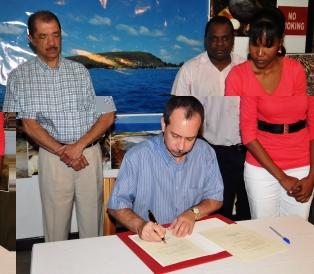 President Michel looks on as Minister Morgan signs the declaration documents. Also witnessing the signing is environment principal secretary Didier Dogley